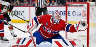 Montreal Canadiens goaltender Samuel Montembeault #35 makes a dramatic diving glove save during an NHL game amidst offseason NHL trade rumors.