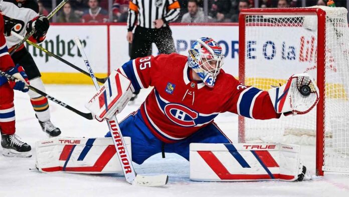Montreal Canadiens goaltender Samuel Montembeault #35 makes a dramatic diving glove save during an NHL game amidst offseason NHL trade rumors.