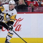 Pittsburgh Penguins captain Sidney Crosby skating on the ice wearing number 87 jersey with prominent Coca-Cola and Jeep logos on the boards in the background.
