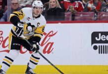 Pittsburgh Penguins captain Sidney Crosby skating on the ice wearing number 87 jersey with prominent Coca-Cola and Jeep logos on the boards in the background.