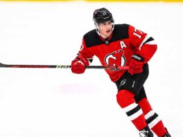 New Jersey Devils defenseman Simon Nemec skating in his red home uniform amidst NHL trade rumors linking him to a move for a top-six forward.