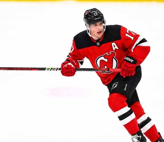 New Jersey Devils defenseman Simon Nemec skating in his red home uniform amidst NHL trade rumors linking him to a move for a top-six forward.