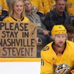 Nashville Predators forward Steven Stamkos skating with the puck at Bridgestone Arena with a fan holding a sign asking him to stay in Nashville.
