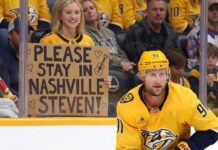 Nashville Predators forward Steven Stamkos skating with the puck at Bridgestone Arena with a fan holding a sign asking him to stay in Nashville.