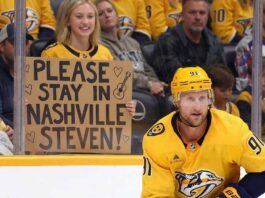 Nashville Predators forward Steven Stamkos skating with the puck at Bridgestone Arena with a fan holding a sign asking him to stay in Nashville.