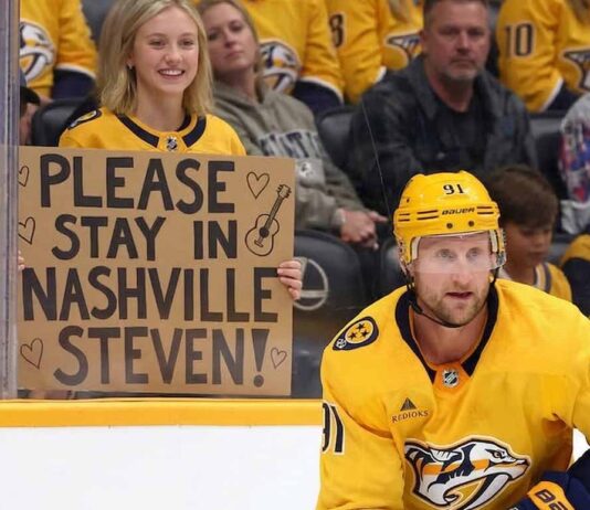 Nashville Predators forward Steven Stamkos skating with the puck at Bridgestone Arena with a fan holding a sign asking him to stay in Nashville.
