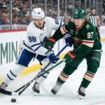 Toronto Maple Leafs' William Nylander (88) and Minnesota Wild's Kirill Kaprizov (97) battle for puck control along the boards during an NHL game.