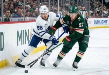 Toronto Maple Leafs' William Nylander (88) and Minnesota Wild's Kirill Kaprizov (97) battle for puck control along the boards during an NHL game.