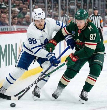 Toronto Maple Leafs' William Nylander (88) and Minnesota Wild's Kirill Kaprizov (97) battle for puck control along the boards during an NHL game.