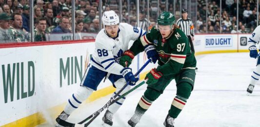 Toronto Maple Leafs' William Nylander (88) and Minnesota Wild's Kirill Kaprizov (97) battle for puck control along the boards during an NHL game.