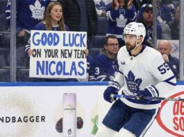 Toronto Maple Leafs center Nicolas Roy skates past a fan holding a "Good Luck On Your New Team" sign, highlighting imminent NHL trade deadline rumors surrounding the forward.