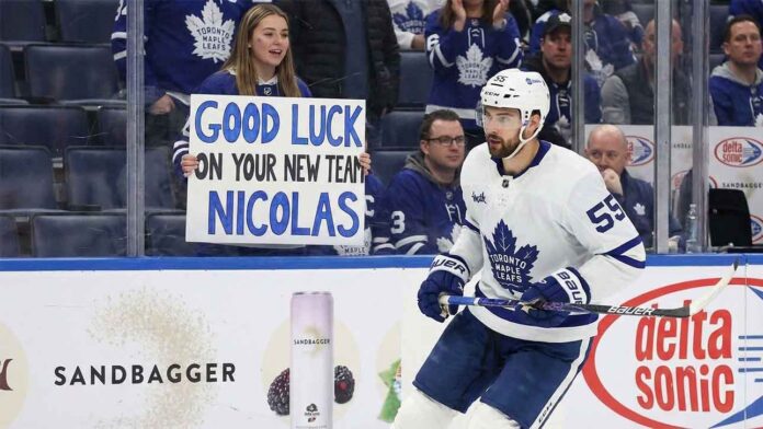Toronto Maple Leafs center Nicolas Roy skates past a fan holding a "Good Luck On Your New Team" sign, highlighting imminent NHL trade deadline rumors surrounding the forward.