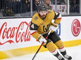 Vegas Golden Knights Salary Cap: Re-Signing Rasmus Andersson Vegas Golden Knights defenseman Rasmus Andersson, wearing the gold number 4 jersey, skates hard on the ice against the boards, illustrating the newly acquired asset facing a difficult offseason contract situation due to the NHL salary cap.