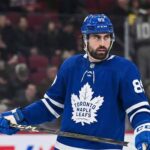 A photo of NHL player Alex Tuch wearing a blue Toronto Maple Leafs home uniform with number 89, holding a hockey stick on the ice, illustrating potential offseason free agency acquisition rumors.