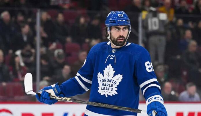 A photo of NHL player Alex Tuch wearing a blue Toronto Maple Leafs home uniform with number 89, holding a hockey stick on the ice, illustrating potential offseason free agency acquisition rumors.