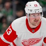 A conceptual photo visualization of current New York Rangers forward Alexis Lafreniere wearing a Detroit Red Wings away jersey, illustrating a potential offseason NHL trade scenario discussed in this post.