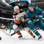 Cutter Gauthier of the Anaheim Ducks and Macklin Celebrini of the San Jose Sharks locked in a fierce battle for control of a loose hockey puck during a crucial NHL game at the SAP Center.