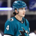 New York Rangers defenseman Braden Schneider pictured in a teal San Jose Sharks uniform, visualizing NHL trade rumors amid NYR rebuild.