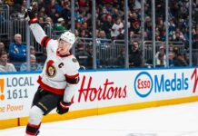 Brady Tkachuk Trade Rumors: Will He Leave the Ottawa Senators? Ottawa Senators captain Brady Tkachuk skating on the ice with his stick raised during a game, amidst escalating NHL trade rumors about his future.