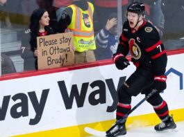 Brady Tkachuk Trade Rumors: Will the Ottawa Senators Move Their Captain? Ottawa Senators captain Brady Tkachuk on the ice wearing the away white jersey amidst NHL trade rumors.
