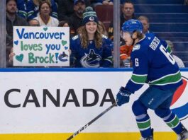Vancouver Canucks forward Brock Boeser skating past a fan holding a handmade sign reading 'Vancouver loves you Brock!' amidst 2025-26 season trade rumors.