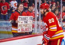 Calgary Flames forward Blake Coleman, wearing jersey number 20, looks at a smiling female fan behind the glass who is holding a hand-made sign that reads "THANKS FOR THE MEMORIES BLAKE!" in an NHL arena.
