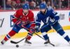 Montreal Canadiens center Nick Suzuki battles a Tampa Bay Lightning forward for puck possession during an intense NHL game.