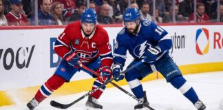Montreal Canadiens center Nick Suzuki battles a Tampa Bay Lightning forward for puck possession during an intense NHL game.