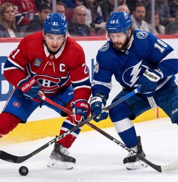 Montreal Canadiens center Nick Suzuki battles a Tampa Bay Lightning forward for puck possession during an intense NHL game.