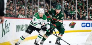 Dallas Stars' Jason Robertson #21 battles Minnesota Wild's Kirill Kaprizov #97 for a loose puck in a tightly contested corner during Game 6 of the 2026 NHL Stanley Cup Playoffs at Xcel Energy Center. The high-resolution photo captures the intensity and focus of two star players in a defining moment of the series.