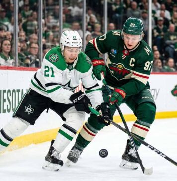 Dallas Stars' Jason Robertson #21 battles Minnesota Wild's Kirill Kaprizov #97 for a loose puck in a tightly contested corner during Game 6 of the 2026 NHL Stanley Cup Playoffs at Xcel Energy Center. The high-resolution photo captures the intensity and focus of two star players in a defining moment of the series.
