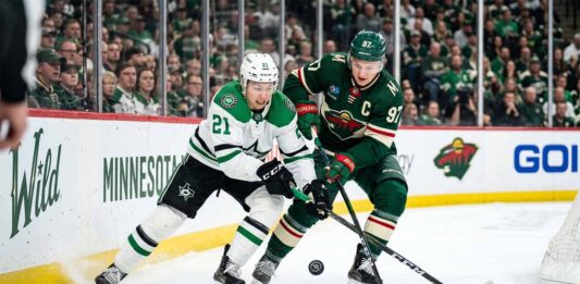 Dallas Stars' Jason Robertson #21 battles Minnesota Wild's Kirill Kaprizov #97 for a loose puck in a tightly contested corner during Game 6 of the 2026 NHL Stanley Cup Playoffs at Xcel Energy Center. The high-resolution photo captures the intensity and focus of two star players in a defining moment of the series.