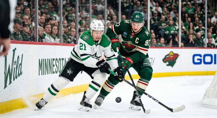 dallas-stars-minnesota-wild-game-6-playoffs Dallas Stars' Jason Robertson #21 battles Minnesota Wild's Kirill Kaprizov #97 for a loose puck in a tightly contested corner during Game 6 of the 2026 NHL Stanley Cup Playoffs at Xcel Energy Center. The high-resolution photo captures the intensity and focus of two star players in a defining moment of the series.