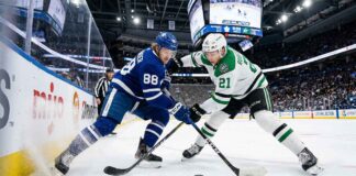Toronto Maple Leafs forward William Nylander (left) and Dallas Stars forward Jason Robertson (right) clash along the boards in a battle for the puck during their NHL matchup.