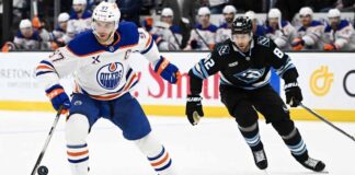 Edmonton Oilers captain Connor McDavid (#97) battles Utah Mammoth forward Kevin Stenlund (#82) for the puck during an intense NHL Western Conference matchup at the Delta Center on April 7, 2026.