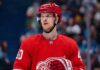 Elias Pettersson Trade Rumors: Will the Detroit Red Wings Acquire the Canucks Star? An NHL action shot featuring superstar center Elias Pettersson wearing a Detroit Red Wings home jersey, with the Red Wings' winged wheel logo.