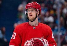 Elias Pettersson Trade Rumors: Will the Detroit Red Wings Acquire the Canucks Star? An NHL action shot featuring superstar center Elias Pettersson wearing a Detroit Red Wings home jersey, with the Red Wings' winged wheel logo.