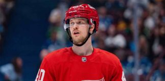 An NHL action shot featuring superstar center Elias Pettersson wearing a Detroit Red Wings home jersey, with the Red Wings' winged wheel logo.