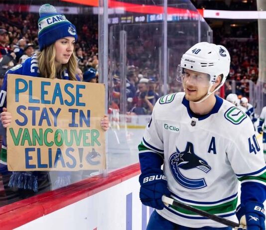 Vancouver Canucks Trade Rumors: Will Elias Pettersson Waive His NMC? A Vancouver Canucks fan holds up a handmade sign behind the glass at Rogers Arena reading "PLEASE STAY IN VANCOUVER ELIAS!" as star center Elias Pettersson (#40) looks on from the ice during an NHL game amidst trade rumors.