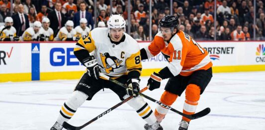 Intense puck battle between Pittsburgh Penguins captain Sidney Crosby (#87) and Philadelphia Flyers forward Travis Konecny (#11) during an NHL Stanley Cup Playoff game.