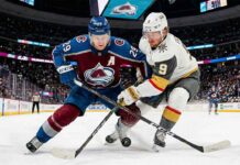 A dynamic photo of Colorado Avalanche center Nathan MacKinnon (#29) battling Vegas Golden Knights center Jack Eichel (#9) for puck possession during a high-stakes NHL game at Ball Arena.