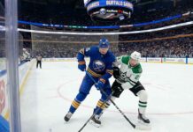 Buffalo Sabres defenseman Rasmus Dahlin (26) in blue battles Dallas Stars forward Jason Robertson (21) in white for the puck during an NHL game at KeyBank Center.