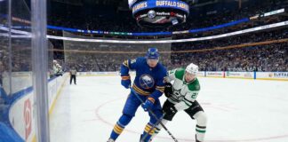 Buffalo Sabres defenseman Rasmus Dahlin (26) in blue battles Dallas Stars forward Jason Robertson (21) in white for the puck during an NHL game at KeyBank Center.
