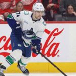 Jake DeBrusk of the Vancouver Canucks skating with the puck during an NHL game, a player whose offseason trade potential is a major point of discussion.