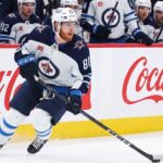 Kyle Connor #81 of the Winnipeg Jets skating with the puck, subject of significant NHL offseason trade rumors, against boards with Coca-Cola logos.