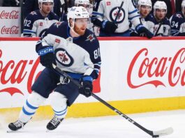 Kyle Connor #81 of the Winnipeg Jets skating with the puck, subject of significant NHL offseason trade rumors, against boards with Coca-Cola logos.