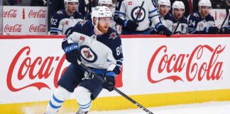 Kyle Connor #81 of the Winnipeg Jets skating with the puck, subject of significant NHL offseason trade rumors, against boards with Coca-Cola logos.