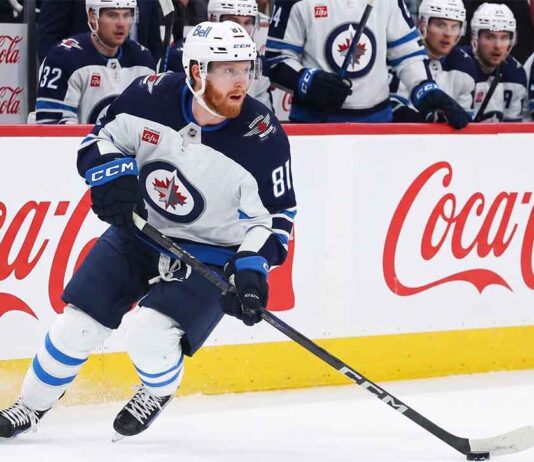 Kyle Connor #81 of the Winnipeg Jets skating with the puck, subject of significant NHL offseason trade rumors, against boards with Coca-Cola logos.