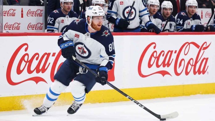 Kyle Connor #81 of the Winnipeg Jets skating with the puck, subject of significant NHL offseason trade rumors, against boards with Coca-Cola logos.