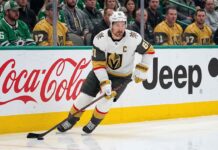 Vegas Golden Knights captain Mark Stone in white jersey skating with the puck during an NHL game, amid speculation regarding his injury history and potential retirement.